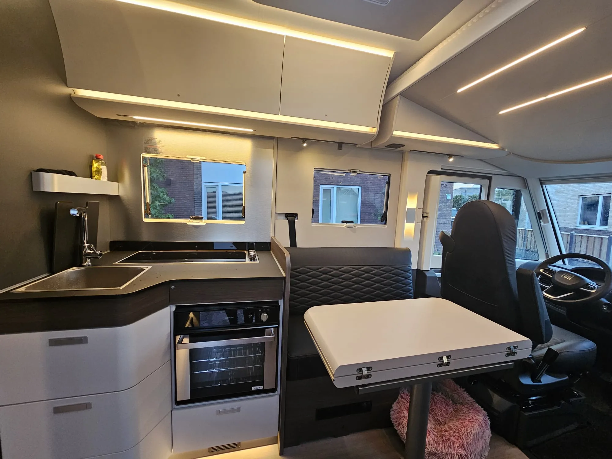 Lichte leefruimte met keuken, eettafel en grote ramen aan de cockpit